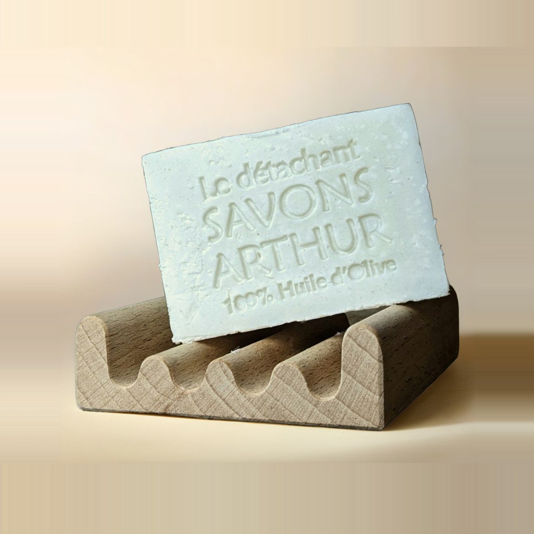 A bar of olive oil soap with its name stamped into it, in a wooden dish, as a listing shot