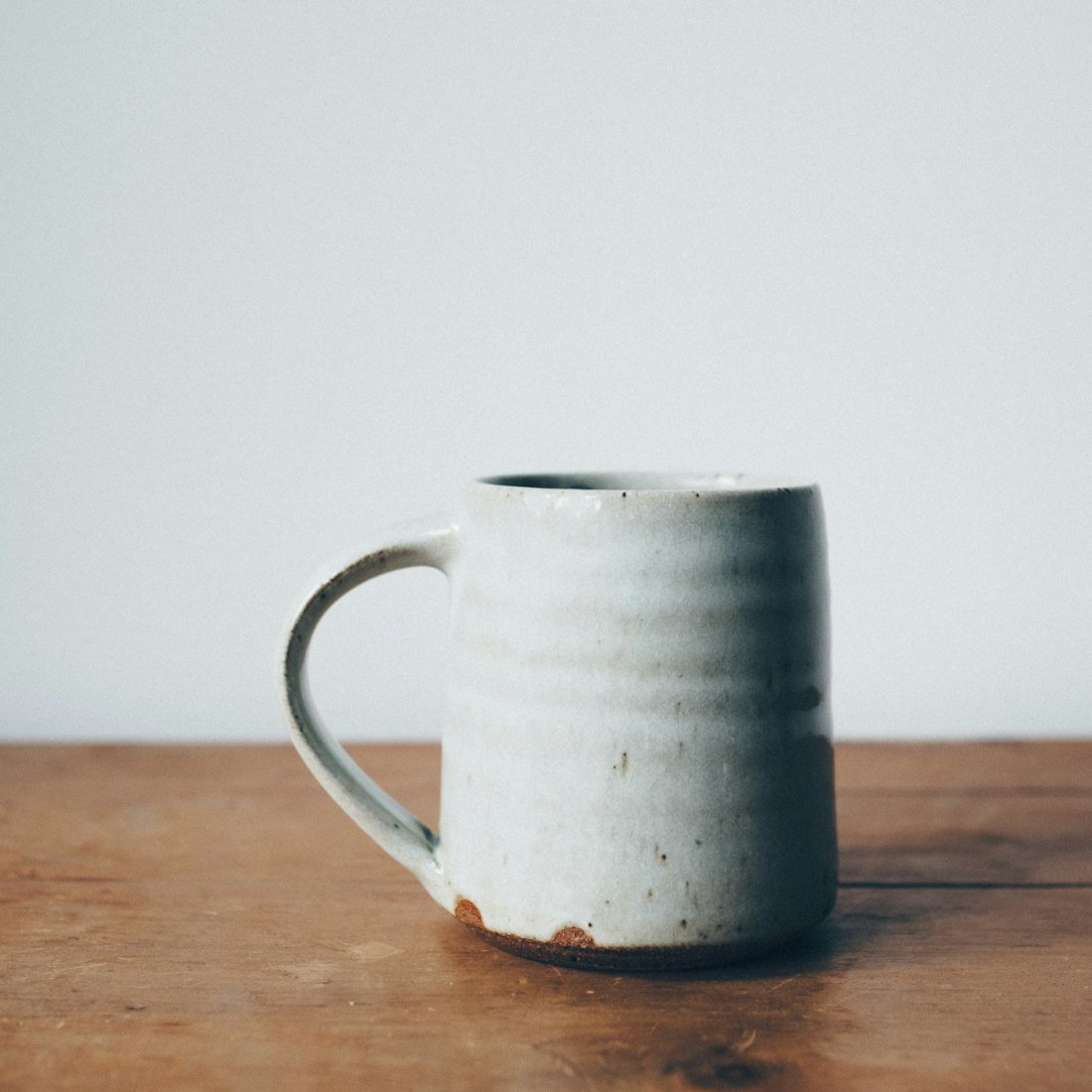 A white stoneware mug with a raw clay foot